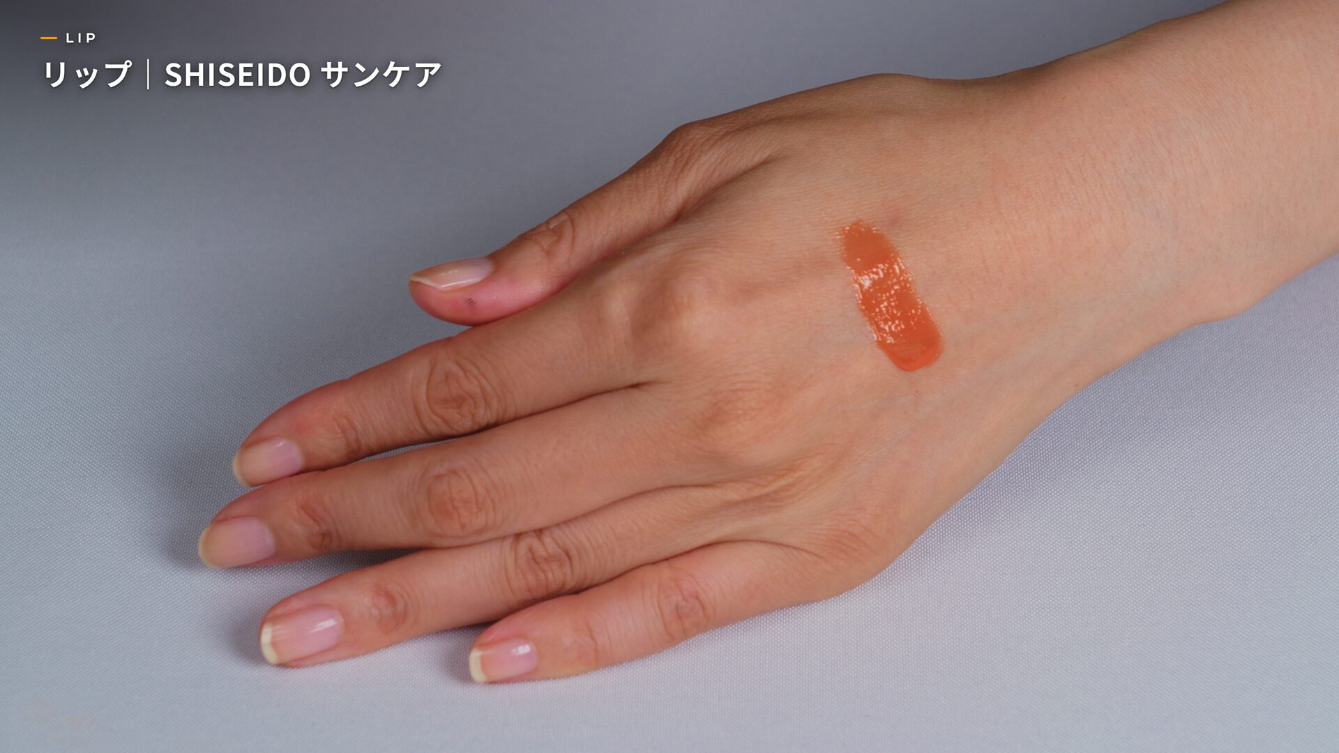 Swatch of Nairobi Orange lip color on the back of a hand