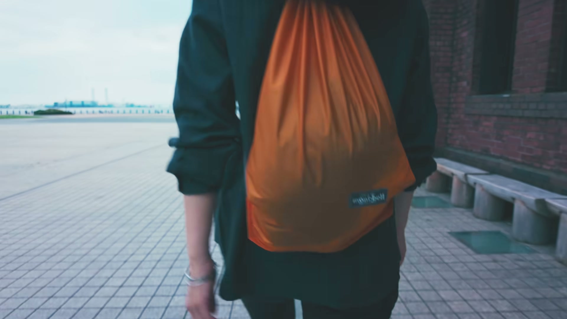 オレンジ色のU.L.ナップサックを背負った後ろ姿