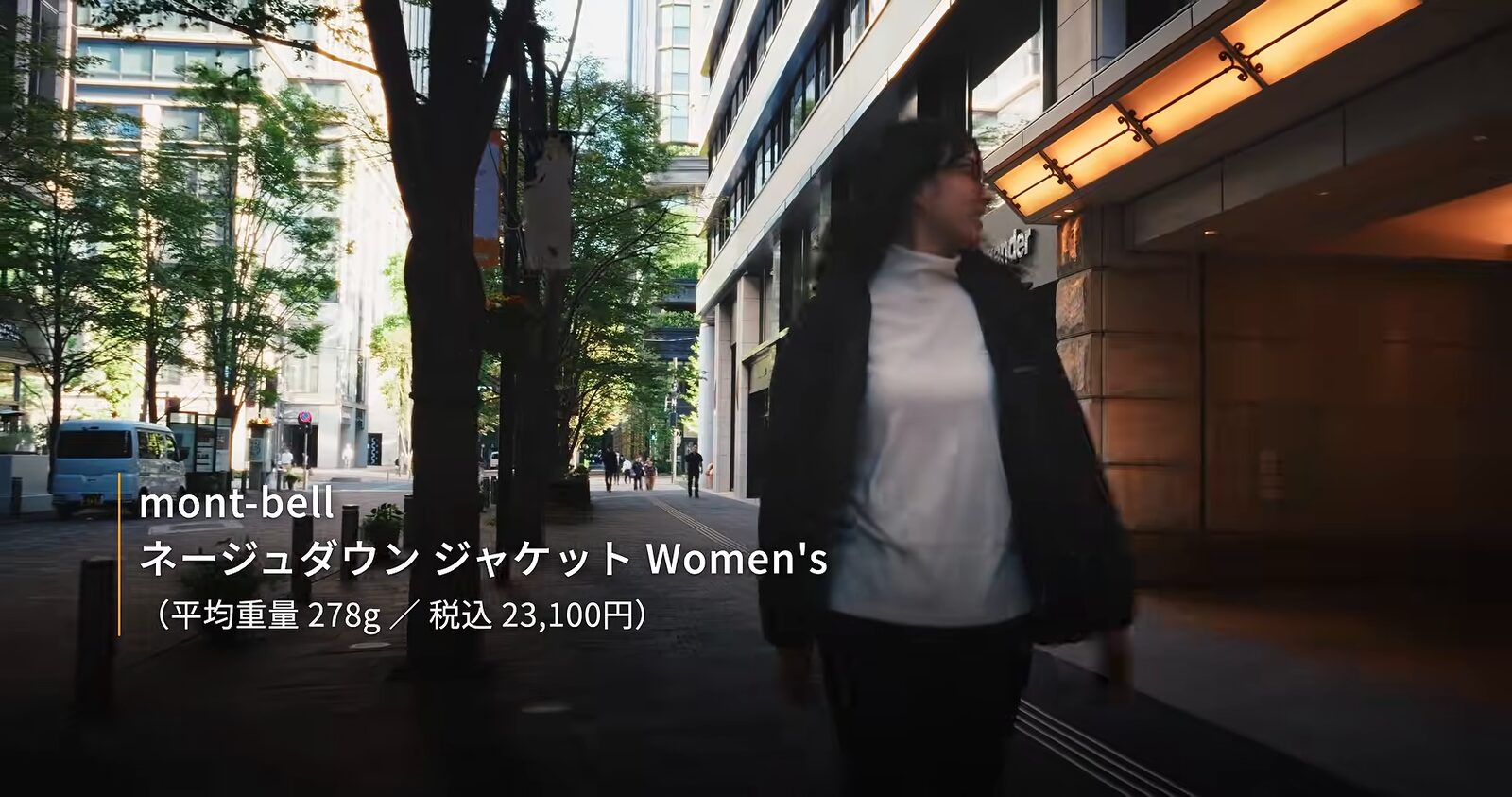 黒のネージュダウン ジャケットに白いトップスを合わせて街を歩く様子