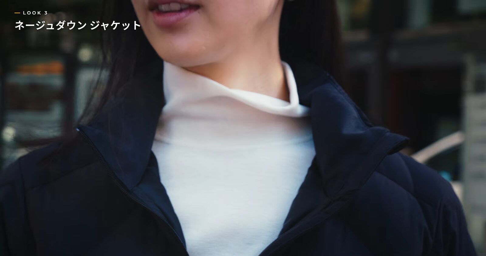 黒いダウンジャケットの襟元から白いハイネックがのぞくアップ