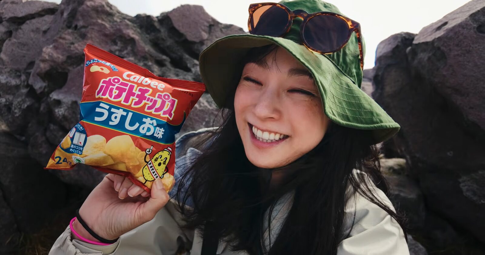気圧でパンパンに膨らんだポテトチップスの袋を持って笑う岩崎良美