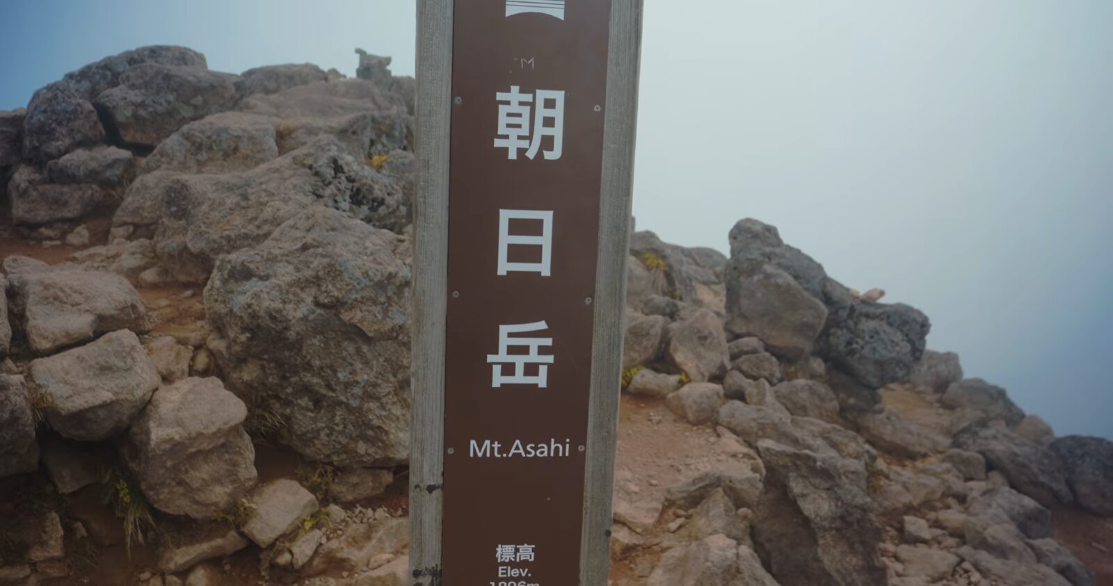 霧に包まれた朝日岳の山頂標識
